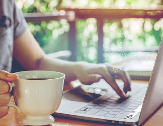 Image: person sitting at desk with laptop open, drinking tea