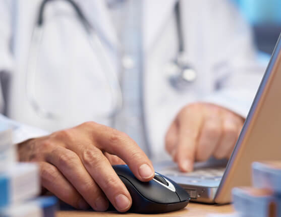 Image: doctor's hands at desk with laptop and mouse
