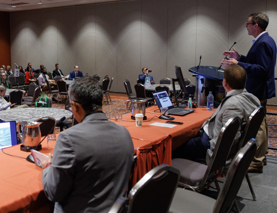 Image: presenters at a head table in front of crowd
