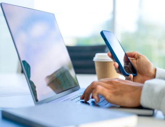 Image: Person on computer and cell phone with coffee